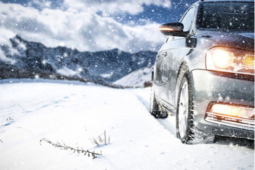 A car on a snowy road, winter driving safety tips concept image